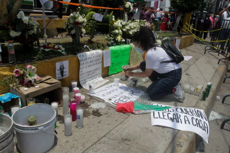Una mujer colocó flores en la ofrenda en honor a las víctimas del derrumbe de la ballena del Metro Olivos de la Línea 12