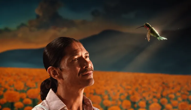 Javier observa un colibrí frente a un campo de cempasúchil en la campaña de Día de Muertos 2026 de Victoria.