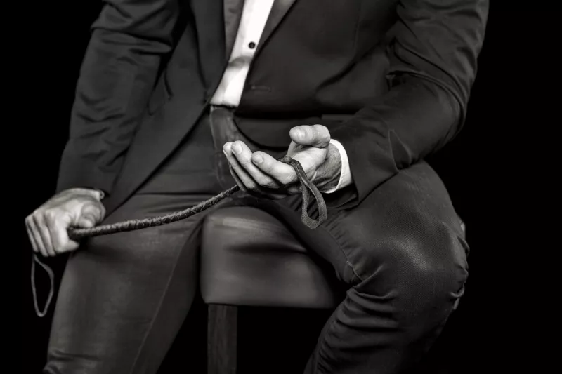 Rich,Man,Sitting,On,Bar,Stool,And,Holding,Whip,,Black