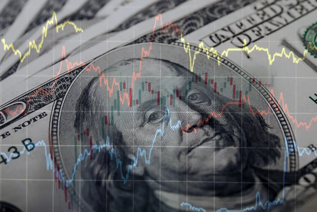 Billete de 100 dólares con estadísticas económicas.