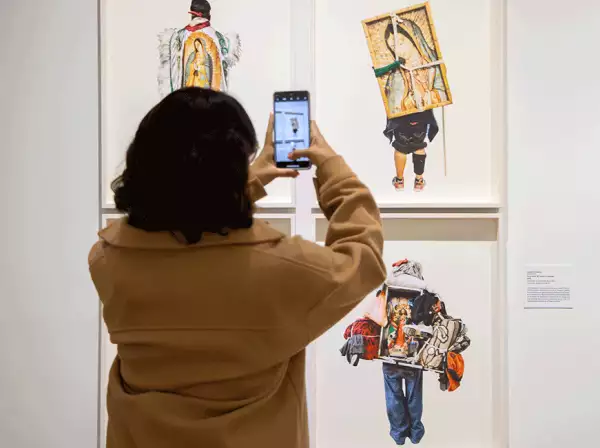 Foto de una mujer frente a una parte de las imágenes que conforman la exhibición Mexichrome.