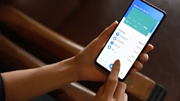 La imagen muestra una mujer consultando su cuenta bancaria y sus gastos mediante su dispositivo móvil. Comodidad y facilidad en la gestión bancaria gracias a la tecnología.