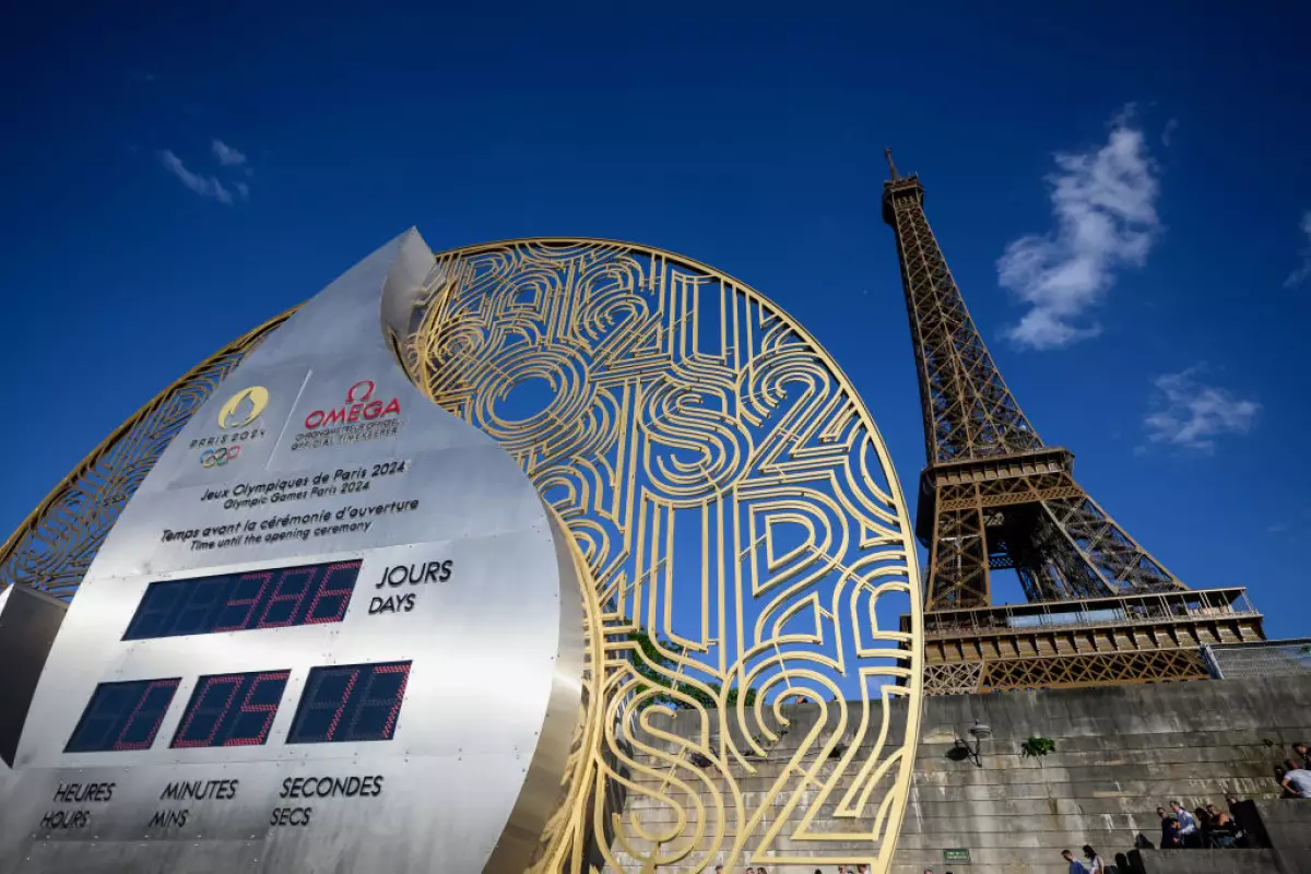 Foto en primer plano del reloj Omega Olympic que lleva la cuenta regresiva para los Juegos Olímpicos 2024, mientras que detrás se alcanza a ver la Torre Eiffel.
