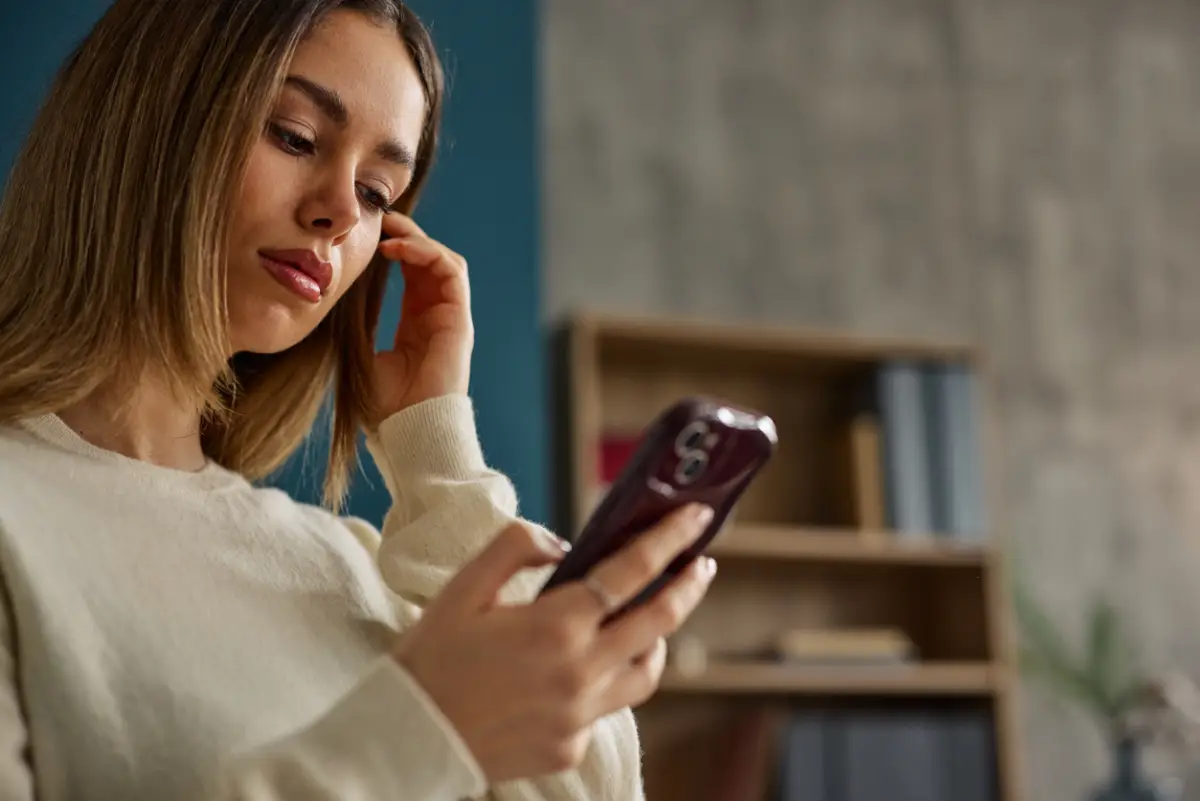 Woman checks her smartphone in a cozy home setting, conveying casual connection and modern communication