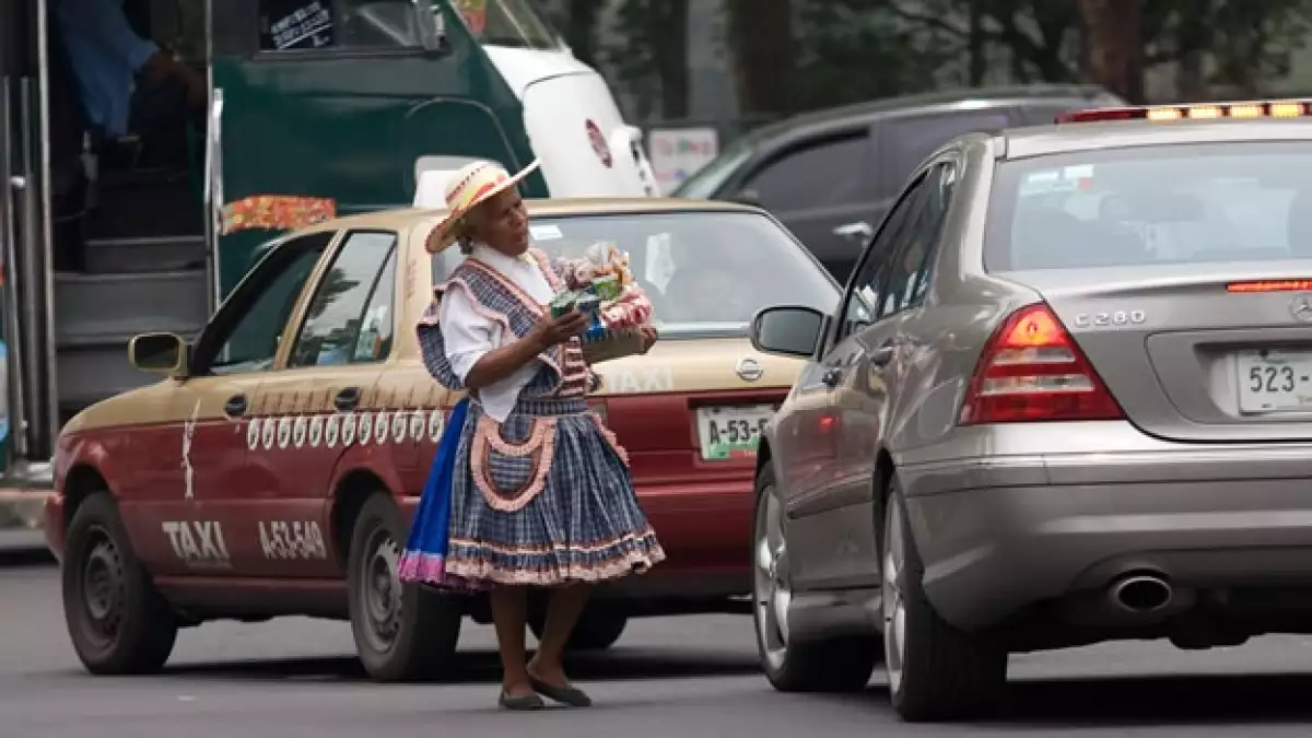 na mujer adulta, ofrece cigarros y dulces en un crucero de la ciudad, muchas de estas personas sufren discriminación y exclusión, además de tener pocas oportunidades para obtener un trabajo formal.