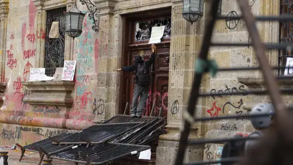 Un integrante del 'bloque negro' frente a una de las puertas vandalizadas del Palacio de Gobierno de Jalisco.
