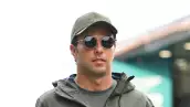 Foto de Checo Pérez con gorra y chamarra verde grisáceo y lentes oscuros