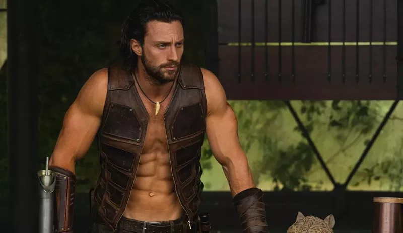 Foto de una escena de 'Kraven', con Aaron Taylor Johnson vestido únicamente con un chaleco y guantes de piel.