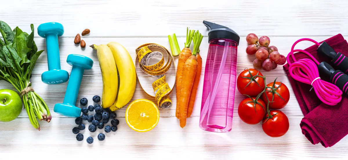 Exercising and healthy food: raibow colored fruits, vegetables and fitness items