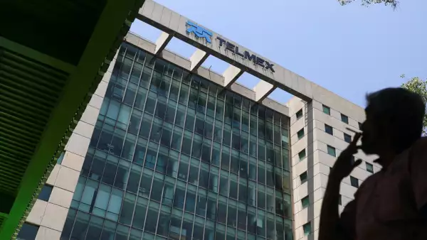 (Una persona fuma frente a un edificio corporativo de Telmex)