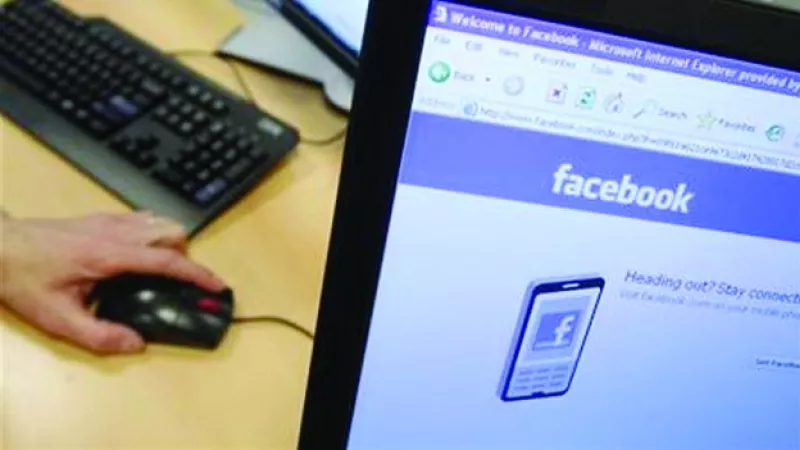 una mano, un mouse y un monitor con facebook