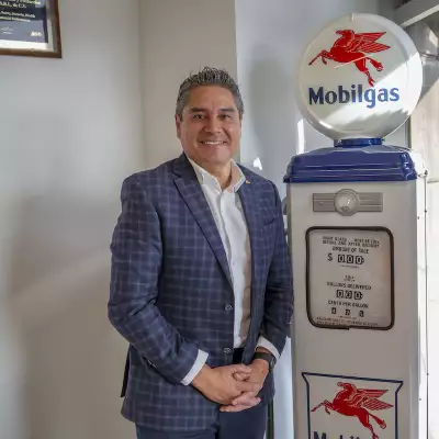 Foto de Alejandro García, director de Marketing para el negocio de combustibles de ExxonMobil en México, posando ante una replica de una bomba despachadora de gasolina antigua con logos de la marca.