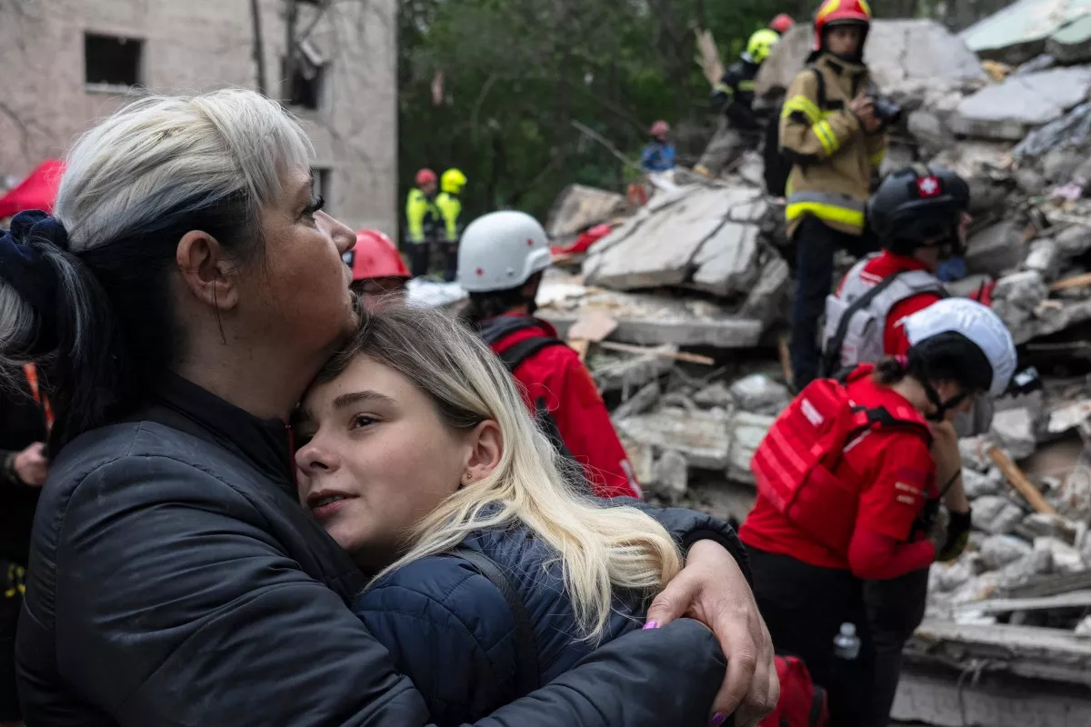 Los residentes locales se consuelan unos a otros mientras los rescatistas ucranianos trabajan entre los escombros de un edificio residencial destruido después de un ataque aéreo en Kiev el 31 de julio de 2025, en medio de la invasión rusa de Ucrania. El presidente ucraniano, el 31 de julio de 2025, instó a sus aliados a provocar un "cambio de régimen" en Rusia, horas después de que un ataque ruso con drones y misiles en Kiev matara a siete personas, incluido un niño de seis años.