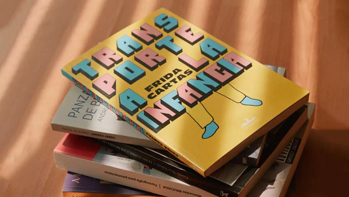 Foto de una pila de libros y hasta arriba se ve el libro 'Transporte a la infancia' de Frida Cartas