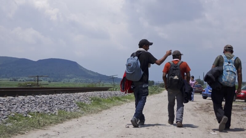 Migrantes caminan por vías del tren