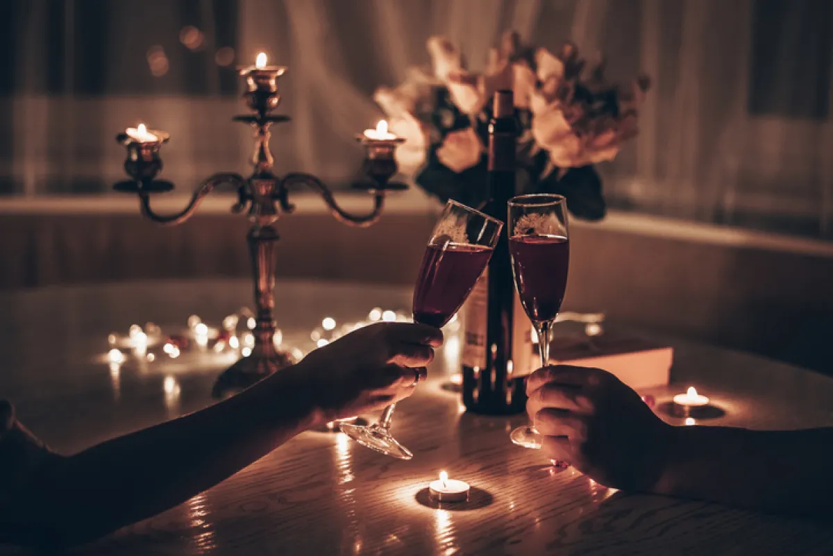 Cena romántica a la luz de las velas en la mesa. Manos hombre y mujer sosteniendo una copa de vino. Cita a la luz de las velas por la noche.