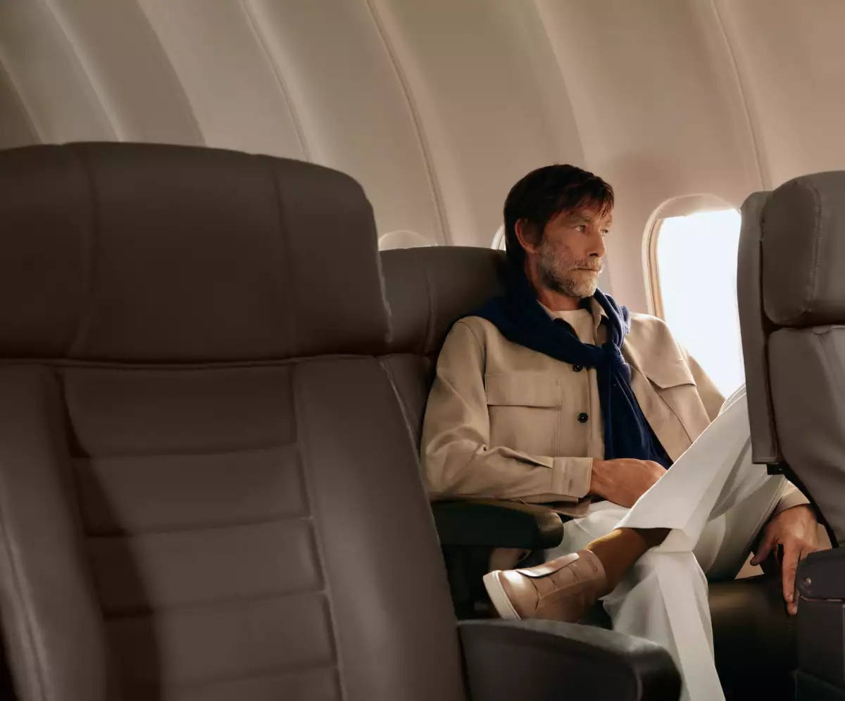 Foto de la marca Zegna de un hombre sentado junto a la ventanilla de un jet privado.