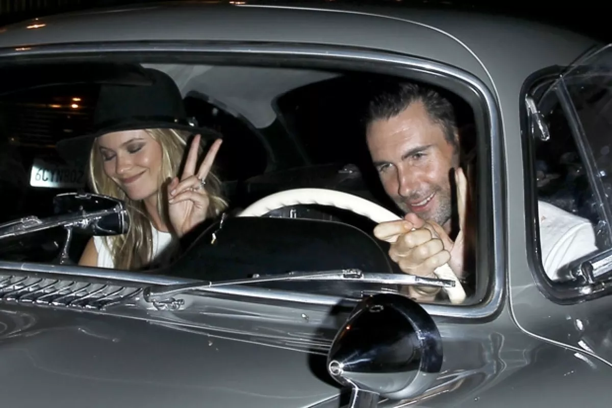 Behati saludó a los paparazzi con una señal de amor y paz, mientras que Adam estaba listo para arrancar su lujoso y clásico auto.