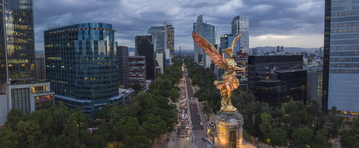 Front aerial view of the statue of the angel of independence on Reforma Avenue with chapultepec forest in the background