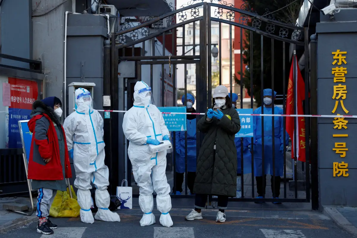 El personal de seguridad con trajes protectores se encuentra en la puerta de un complejo residencial que está cerrado mientras continúan los brotes de la enfermedad por coronavirus (COVID-19) en Beijing, el 22 de octubre de 2022.