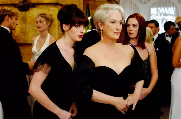 Foto de una escena de 'El Diablo viste a la moda' con Anne Hathaway hablándole al oído a Meryl Streep en sus papeles de Andy Sachs y Miranda Priestly respectivamente, ambas vestidas de gala.