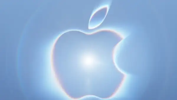 Logo de Apple iluminado por una luz blanca en un fondo color azul.