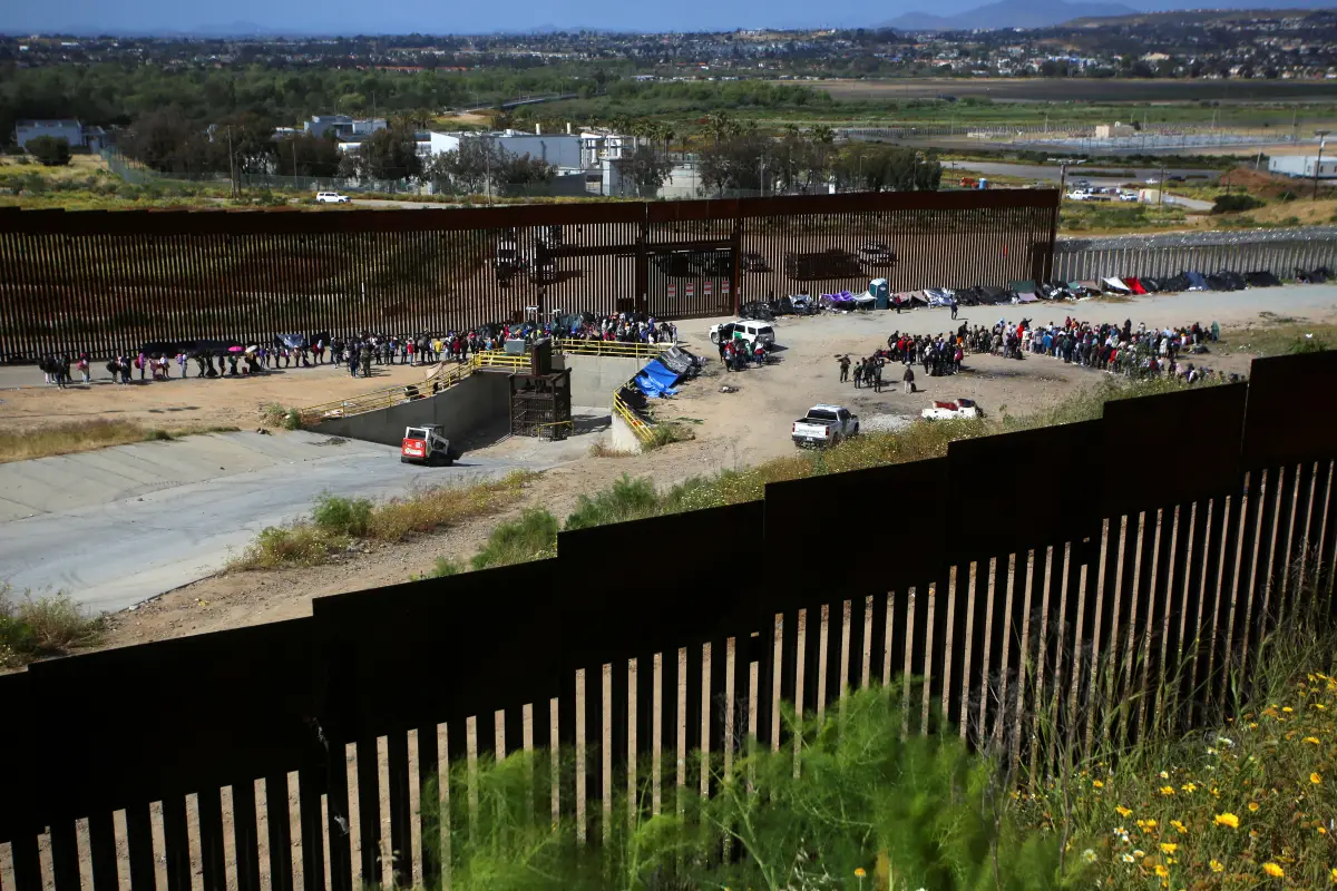 Los migrantes se reúnen entre las vallas fronterizas primaria y secundaria en San Diego mientras Estados Unidos se prepara para levantar las restricciones de la era COVID-19 conocidas como Título 42, que han impedido que los migrantes en la frontera entre Estados Unidos y México busquen asilo desde 2020, como se ve desde Tijuana, México, el 8 de mayo de 2023.