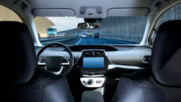 Cockpit of driverless car driving on highway viewed from rear seat.
