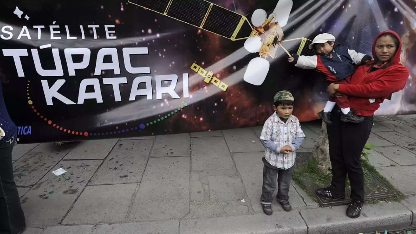 personas junto a un letrero del satelite tipac katari