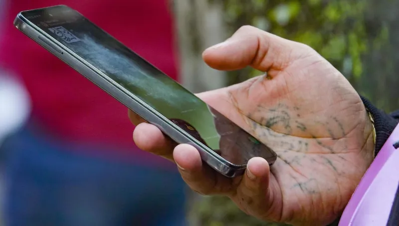 Una mano con un tatuaje en la palma sostiene un celular. 