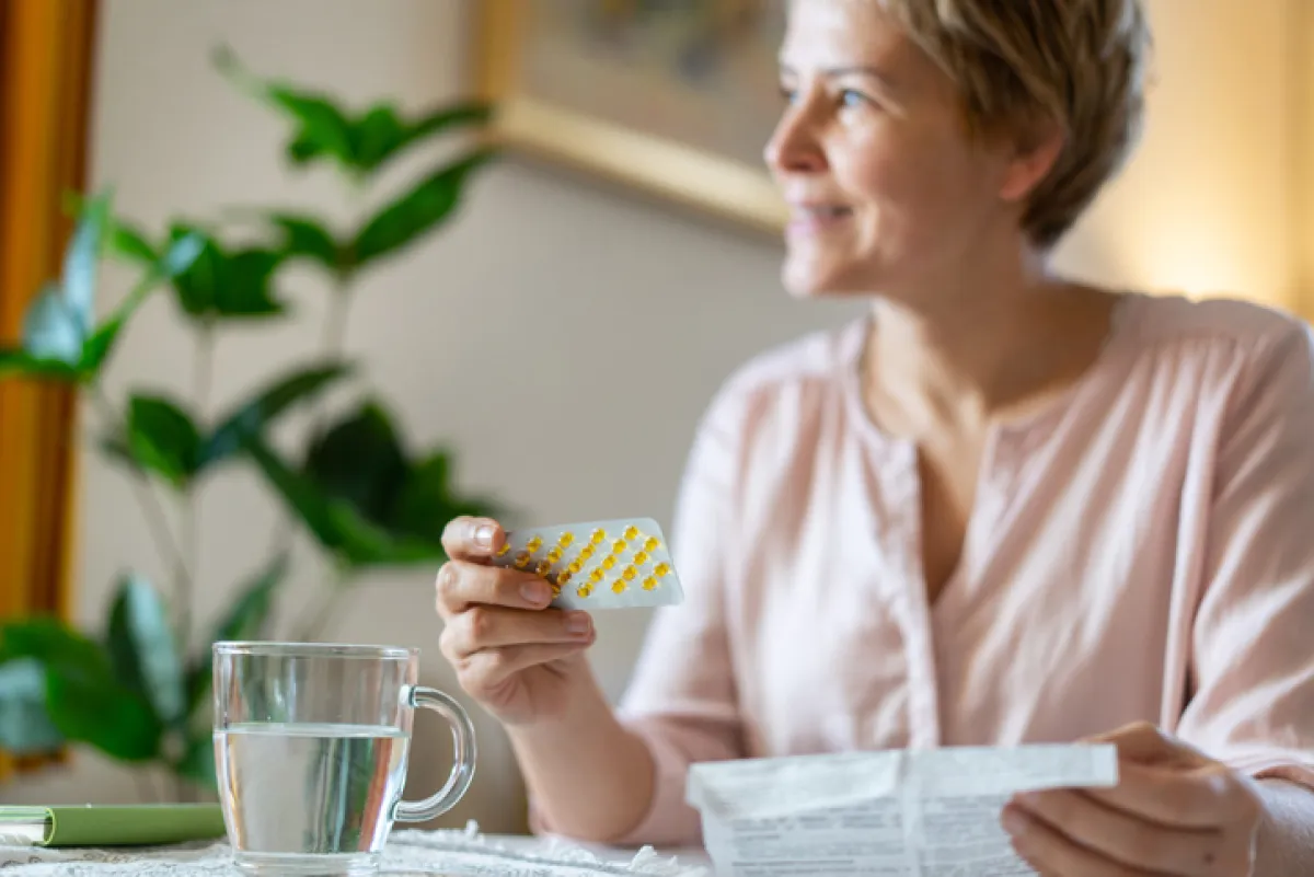 A smiling woman is relieved to get her HRT pills