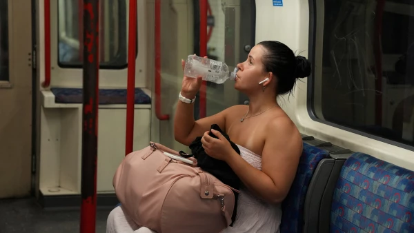 Una mujer bebe agua mientras viaja en el metro de Londres durante una ola de calor en Londres, Gran Bretaña.