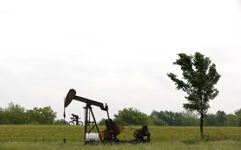 Un hombre pasa en bicicleta junto a un campo de petróleo en Estados Unidos, en Oklahoma.