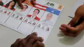Un trabajador electoral muestra materiales electorales a un votante, una semana tarde en una elección especial después de que el partido gobernante local siguiera votando cerrado el día de las elecciones, en medio de acusaciones de sabotaje y fraude, en una carrera presidencial aún demasiado cerca para llamar mientras continúa el conteo, en San Antonio de Flores, Honduras, el 7 de diciembre de 2025.
