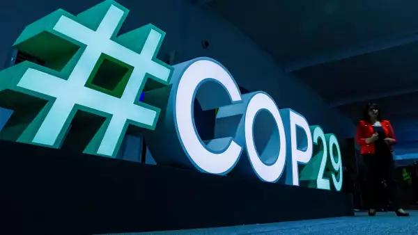 A woman passes by a #COP29 sign during the United Nations climate change conference COP29 in Baku