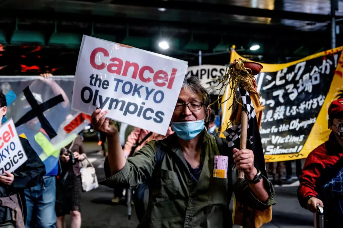A protester holds a placard that says 'Cancel the Tokyo