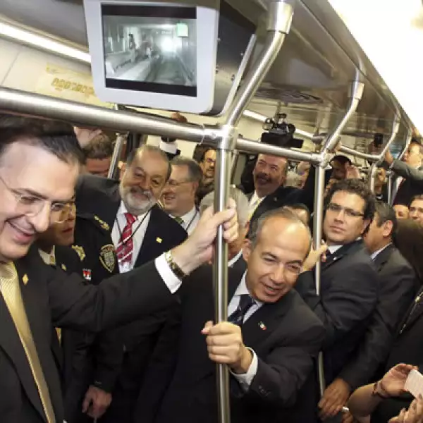 Marcelo Ebrard (izq), Carlos Slim (centro al fondo), y Felipe Calderón (der), sonrientes durante el viaje en metro de inauguración.