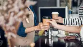 Barista entregando café en vaso para llevar al comensal