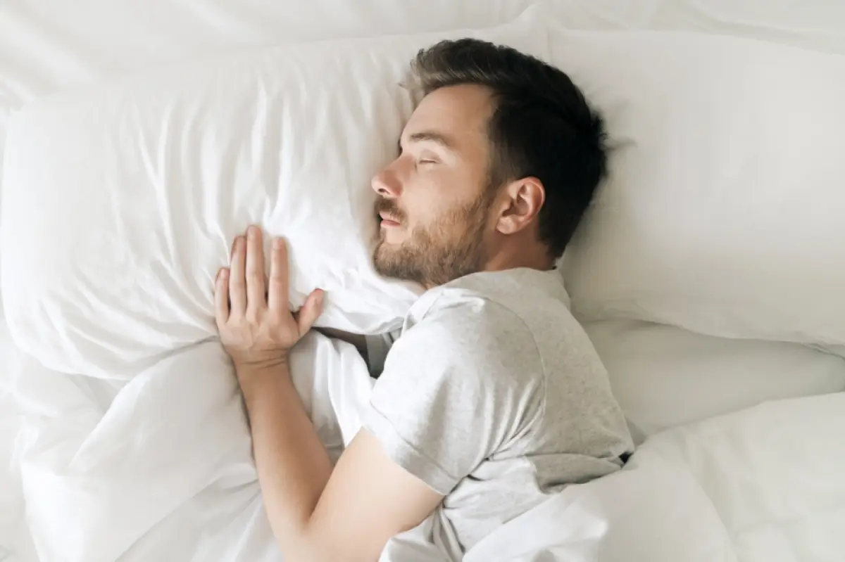 Hombre durmiendo sobre dos almohadas