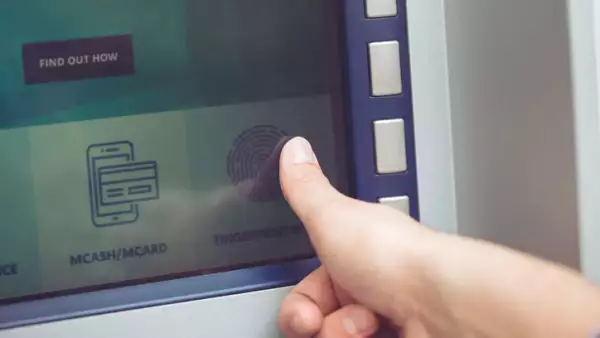 Woman at ATM using fingerprint recognition technology