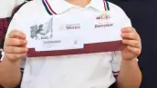 Un alumno de educación básica sostiene el sobre de la tarjeta del Banco del Bienestar donde el gobierno federal le depositará el monto del programa social de becas.