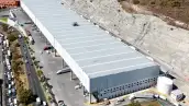 Imagen aérea de una nave industrial junto a una avenida. 