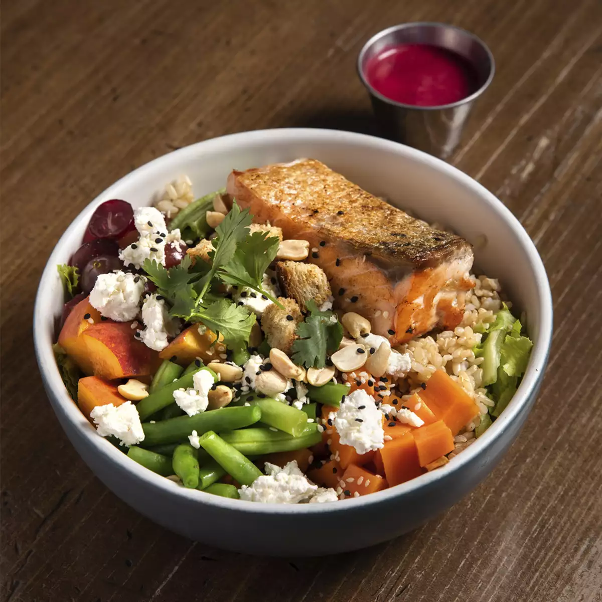 Foto de plato de ensalada con salmon, queso feta, zanahoritas y cus cus.