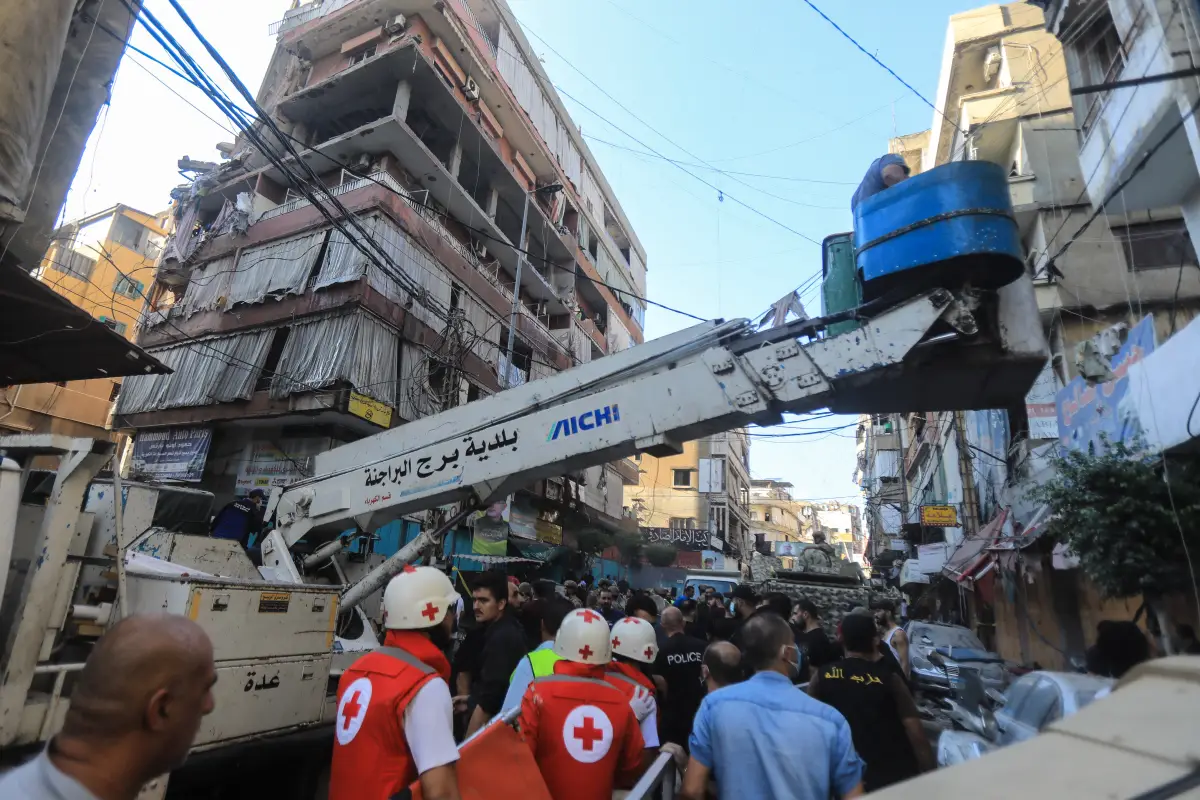 Los rescatistas trabajan en una calle bajo un edificio residencial cuyas dos plantas superiores (izquierda) fueron impactadas por un ataque israelí en el área de Ghobeiri, en los suburbios del sur de Beirut, el 24 de septiembre de 2024.