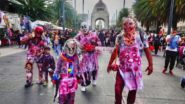 Tres adultos y dos niños con batas y máscaras de látex llenas de sangre caminando por avenida Revolución.jpg
