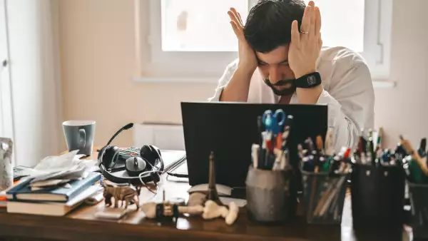 Tired frustrated exhausted businessman working from home online sitting at home office with laptop during quarantine and self isolation period at pandemic. Crisis management. Despair of market falling down.