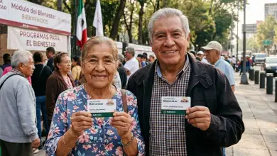 Dos adultos  mayores sosteniendo una tarjeta de la Pensión del Bienestar.