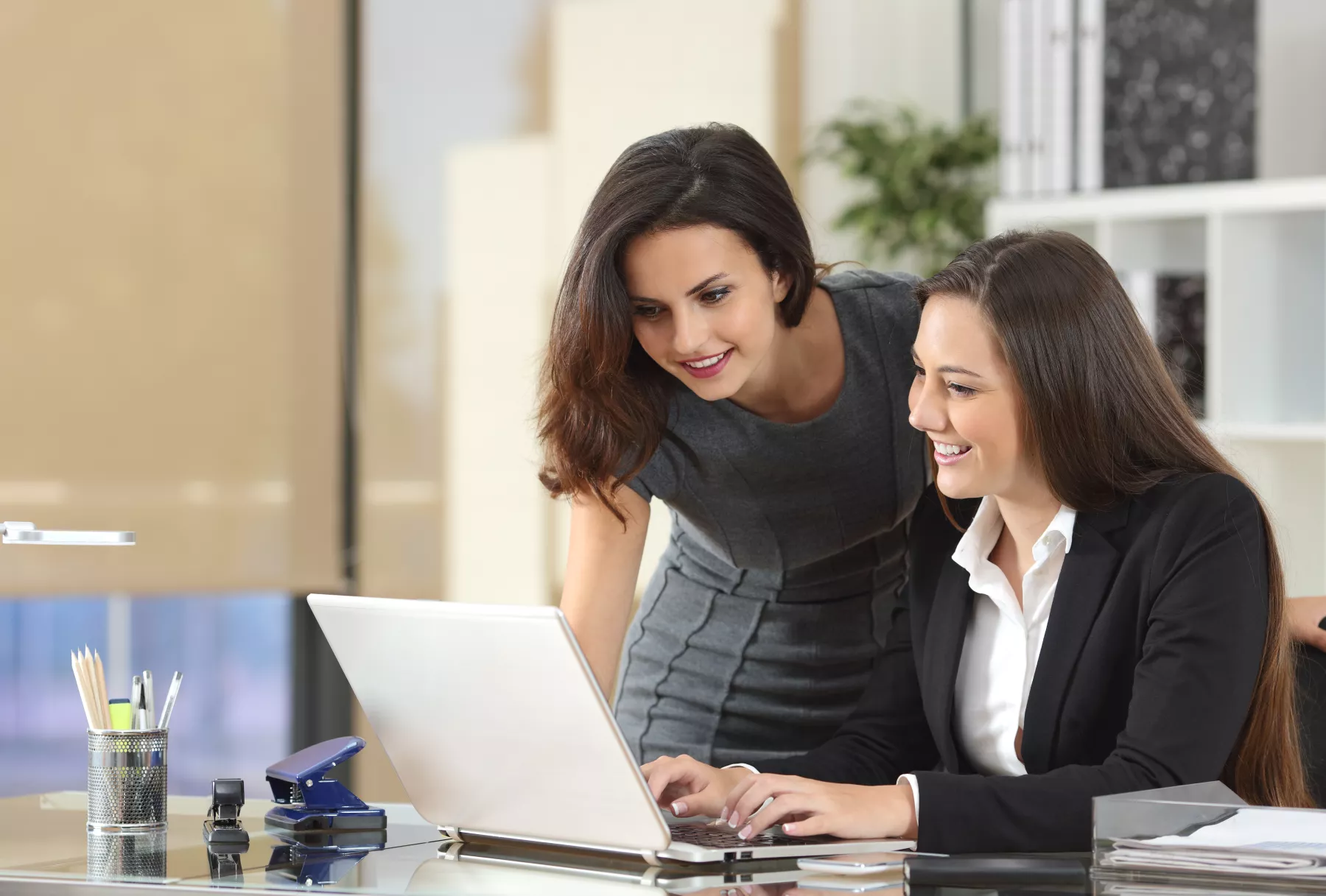 Dos mujeres con puestos ejecutivos frente a una computadora planean el siguiente proyecto laboral