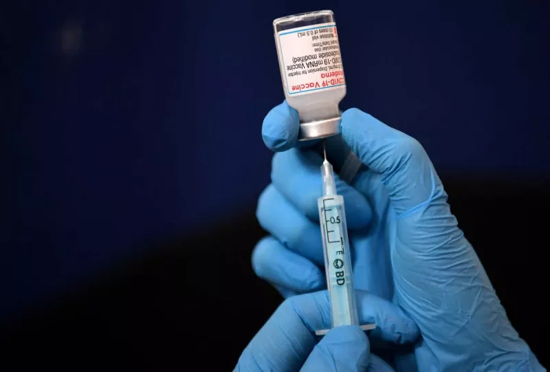 La vacunación obligatoria debe ser el último recurso (Manos de personal médico, sostienen una jeringa que contiene la vacuna contra covid 19)