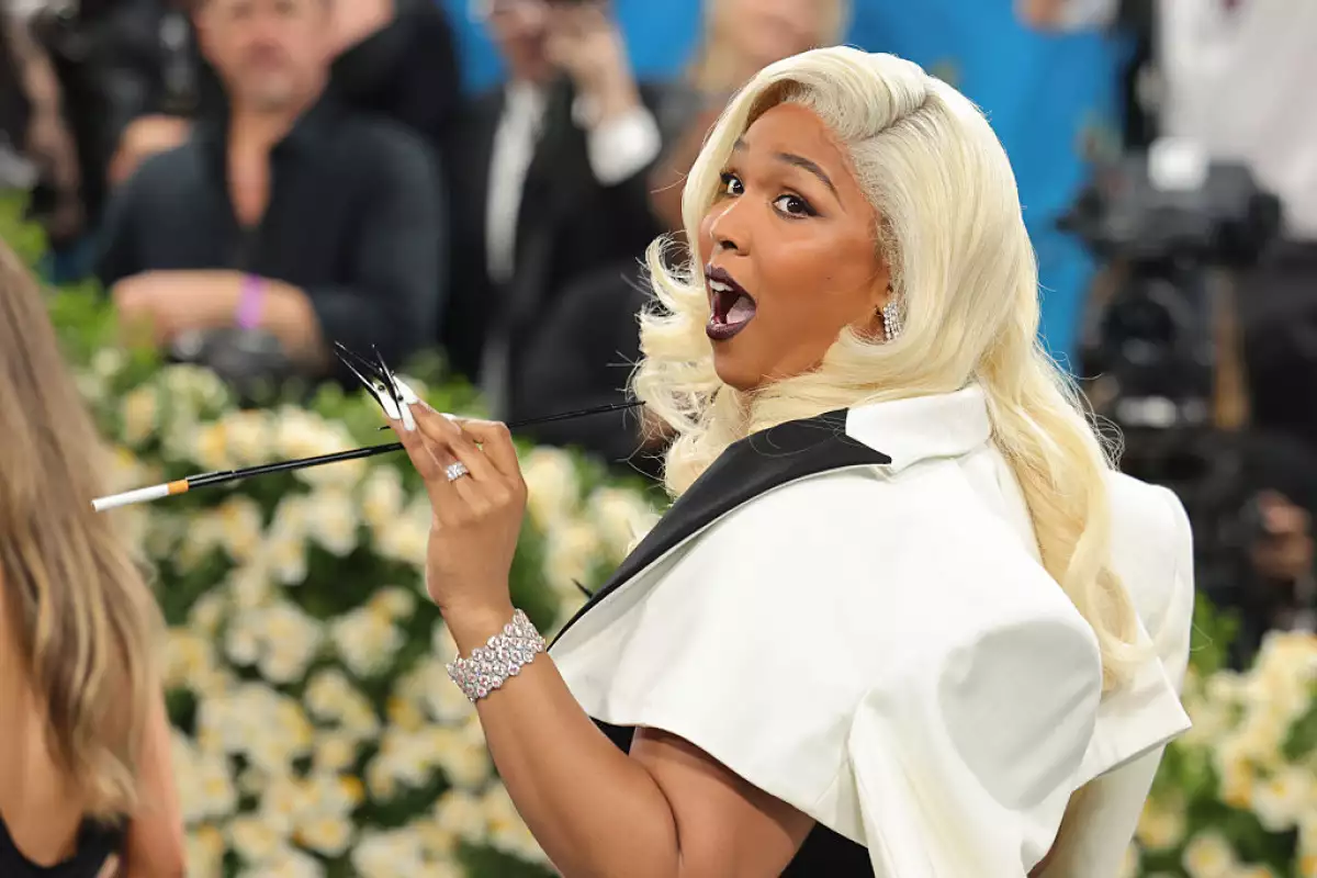 Foto de Lizzo a la llegada de la MET Gala 2025 con cabello rubio y labios pintados de negro.